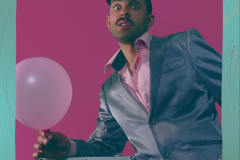 Ciemnoskóry mężczyzna trzyma w ręce różowy balon.