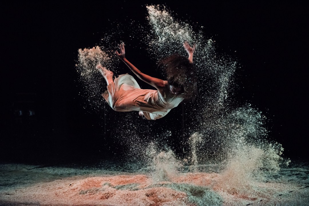 Zdjęcie kobiety podczas skoku. Znajduje się w powietrzu nad piachem.