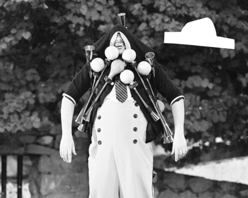 Czarno-biała fotografia clowna, który ma przymocowane do ubrania wiele instrumentów.